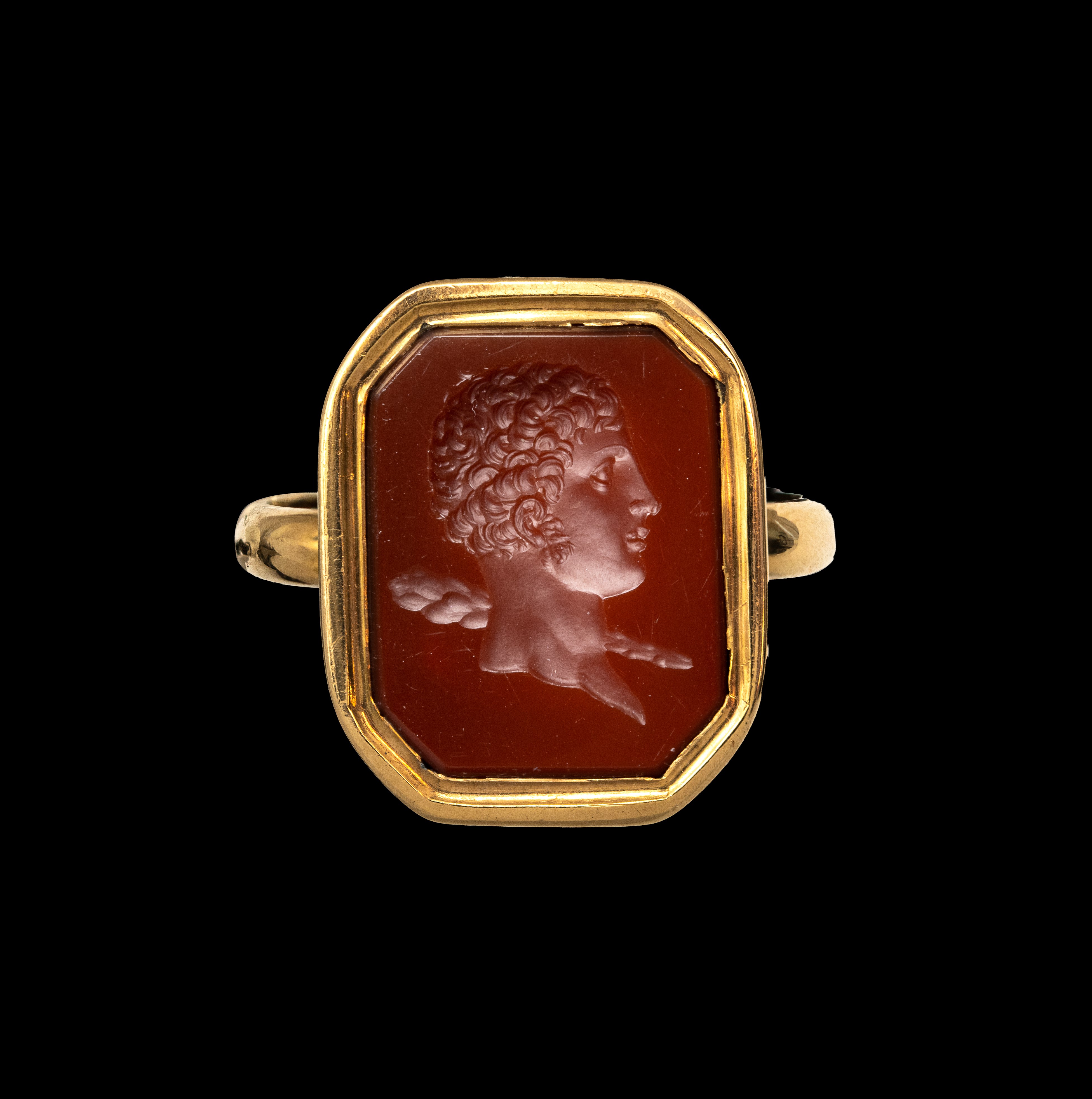 A 19th century gold ring set with a neoclassical carnelian intaglio. Bust of young Hercules. 